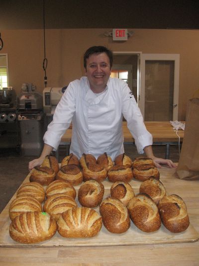 an exhausted looking Mark posing in front of a bench full of bread