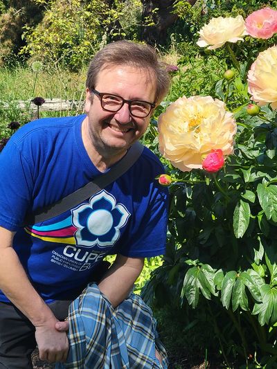 Mark posing beside a massive yellow-white peony flower, Beacon Hill Park. The bloom is nearly as big as his head.