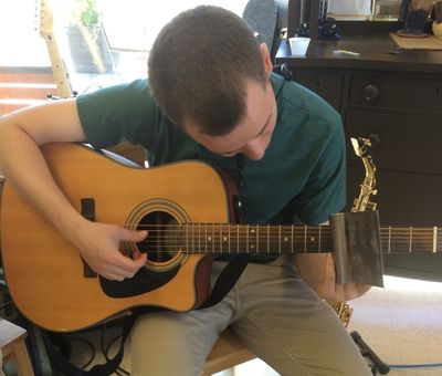 Chris playing slide guitar with a bench scraper